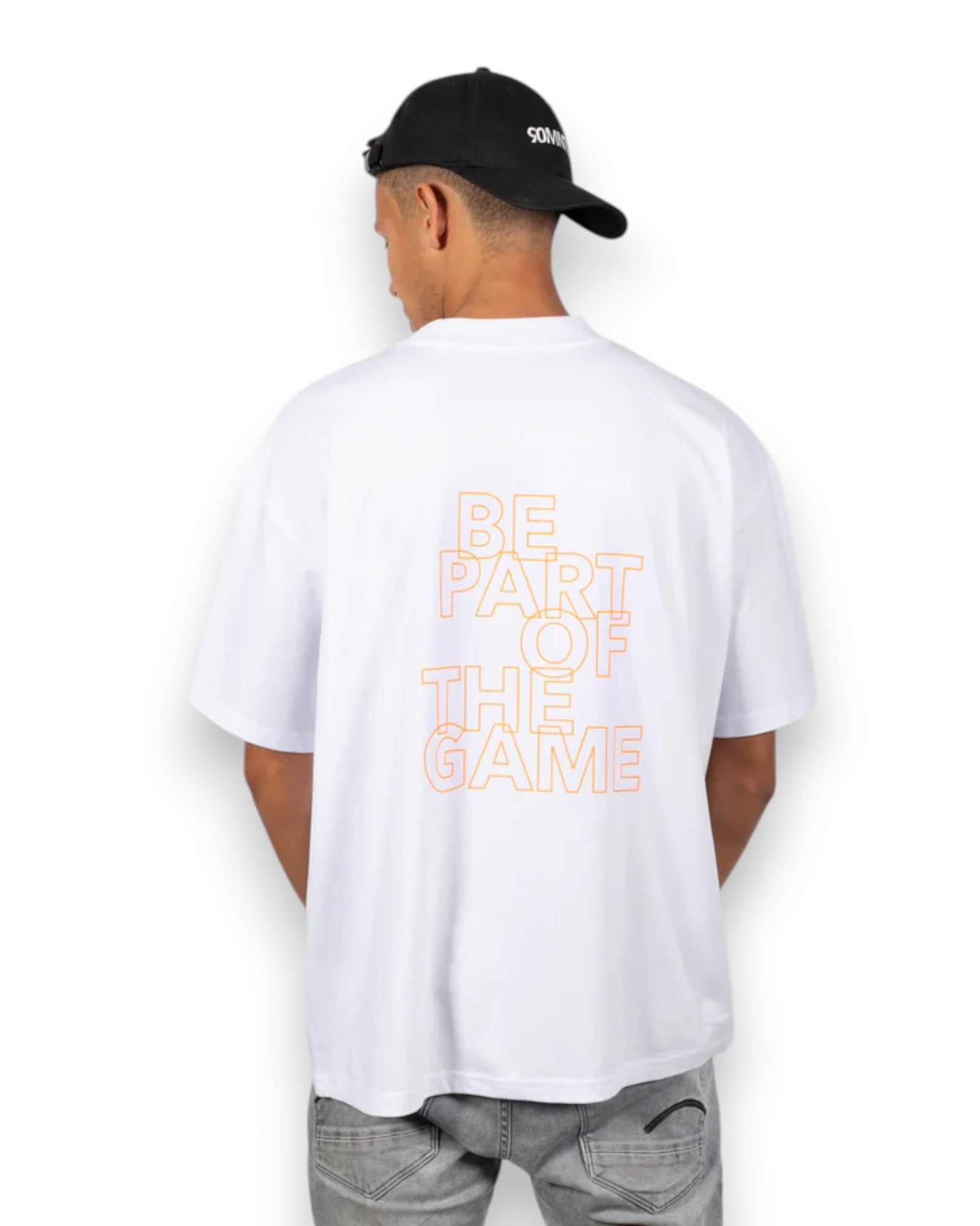 Model mit Cap trägt BE PART OF THE GAME Oversized T-Shirt in weiß mit orangenen Print - Rückansicht